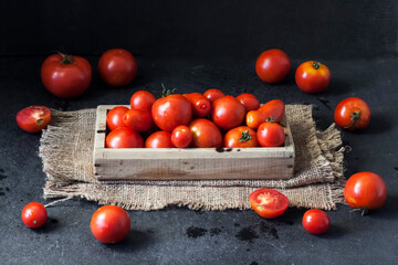 Fototapeta na wymiar Fresh red tomatoes in wooden box on black background