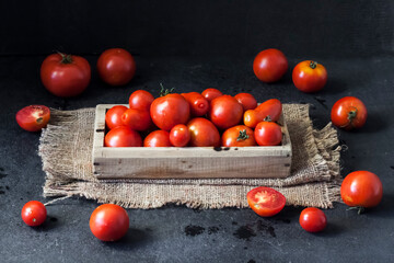 Fresh red tomatoes in wooden box on black background