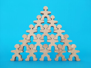 Teamwork and cooperation concept, wooden people standing shoulder to shoulder forming a pyramid