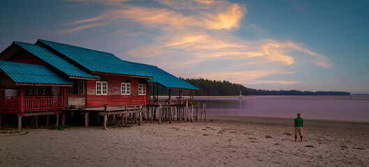 Cute wooden house by the beach and man standing on the sand