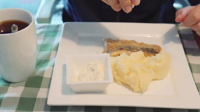 Male hands squeeze lemon on fried fish fillet of pollock or whiting fish for lunch in a restaurant. Close-up.