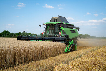 Obraz premium Getreideernte - Moderner Mähdrescher bei trockenem Erntewetter auf dem Feld im Einsatz.