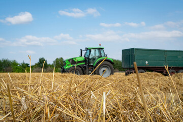 Getreideernte - am Feldrand wartet ein Schlepper mit Transportanhänger auf die Entladung des Mähdreschers.