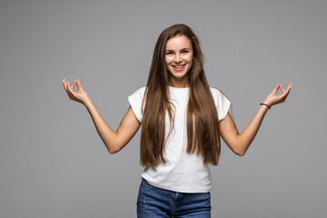 Happy smiling young woman gesturing with hands and showing balance isolated on gray background