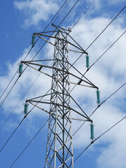 High voltage power lines pylons and electrical cables on a clear blue sky