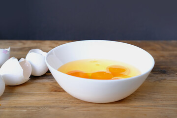 raw chicken eggs in a white cup on the table, broken shells, the concept of cooking scrambled eggs, omelet, home cooking