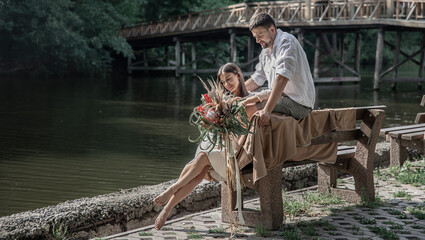 Fototapeta na wymiar Young married couple in a park near the river, on a date in nature.