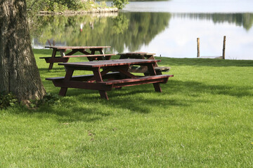 Closeup shot of a bench near a clear lake and greenery-covered hills