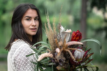Portrait of an attractive young woman with a bouquet of exotic protea flowers.