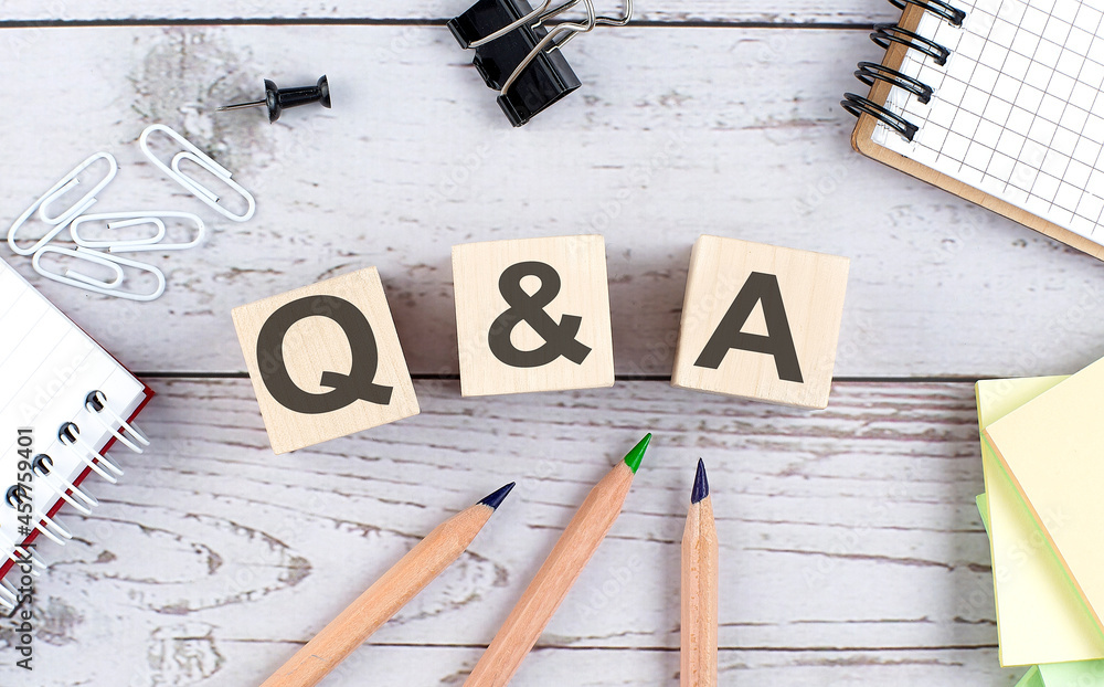 Poster q and a text on wooden block with office tools on wooden background