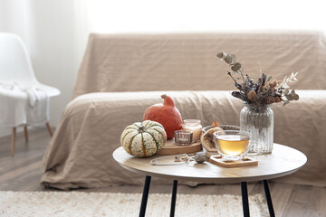 Autumn composition with tea and pumpkins in the interior of the room.