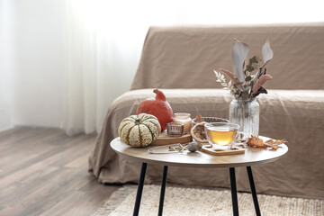 Autumn composition with tea and pumpkins in the interior of the room.