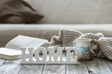 Decorative word home, cup, book and knitted element in the interior of the room.