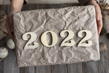 Close up of wrapped New Year gift with numbers 2022 in female hands.
