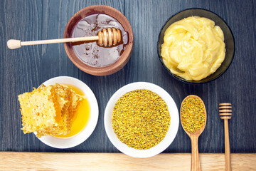 Fresh flower honey of different varieties, pollen and honeycomb with spoons on a wooden background....