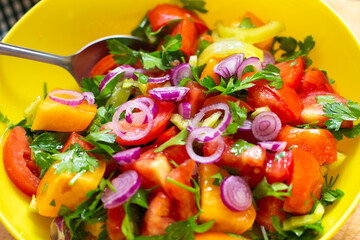 Colorful salad of fresh vegetables in a cup, close-up. Cooking tomato, pepper and onion snacks