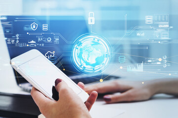 Businesswoman holds smartphone in her hands and works on laptop