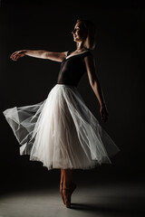 ballerina with a white dress and black top posing on gray background. © Nikola Spasenoski