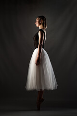 ballerina with a white dress and black top posing on gray background. © Nikola Spasenoski