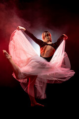ballerina with a white dress and black top posing on red smoke background © Nikola Spasenoski
