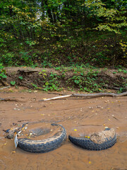 Tires in the sand at the bottom of the stream. Bad ecology
