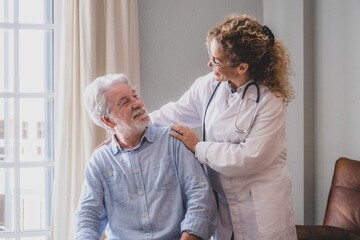Obraz premium Young female doctor encouraging senior man at home. Doctor helping senior patient and giving care. Female homecaregiver taking care of retired old man. Old man and physician talking at nursing home
