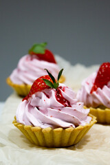 Sumptuous mini tarts adorned with luscious pink cream and topped with a fresh strawberry, embodying elegance and taste.