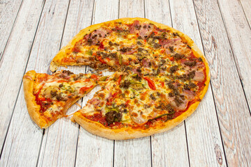 Pizza with minced meat, red peppers, slices of smoked bacon, tomato and oregano with onion and mozzarella cheese