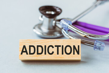 Stethoscope with ADDICTION words on wooden cube.