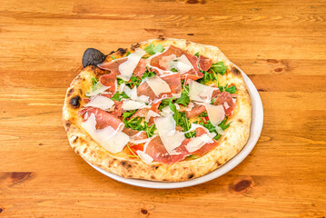 Italian Arugula Pizza with Nuts, Parmesan Cheese Slices and Prosciutto with Tomato and Mozzarella