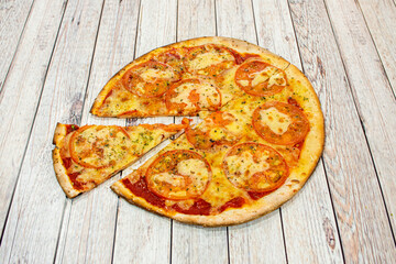 Thin crust pizza with thin tomato slices, melted mozzarella cheese, tomato sauce and oregano cooked in a stone oven