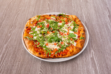 Italian pizza with arugula and basil leaves, mozzarella cheese with tomato cubes and parmesan cheese in quantity cooked in a stone oven