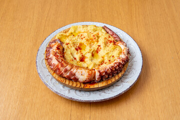Grilled octopus tentacle with mashed potatoes with paprika and olive oil on wooden plate