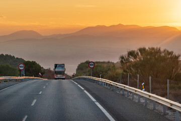 Food tanker truck driving on a mountain road at sunrise.