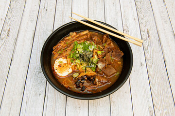 spicy beef ramen with miso, boiled bamboo, boiled egg, chives, nori seaweed and chopsticks