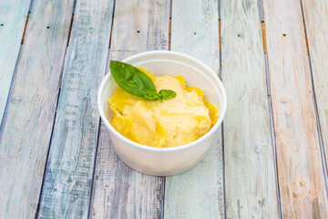 Ravioli filled with four cheese sauce and grated cheese with basil inside a take away container
