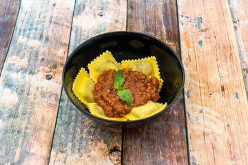 Delicious meat filled ravioli with bolognese sauce and basil leaves on top