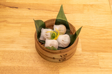 Pork and chives dumplings. Kao stuffed with steamed pork on banana leaves in traditional wooden container