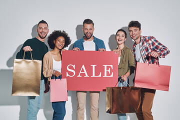 Group of young beautiful people in casual clothing carrying shopping bags and smiling