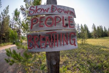 Sign - Slow Down People Breathing along a dirt word to prevent motorists from kicking up dust with...