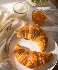 Continental breakfast - delicious ruddy croissants, orange jam and fresh milk on a white silk tablecloth. Restaurant, hotel, cafe, cookbook, culinary blog.