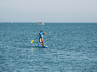 Paddle boarder. Sportsman paddling on stand up paddleboard. SUP surfing. Active lifestyle. Outdoor recreation. Vacation on seaside.