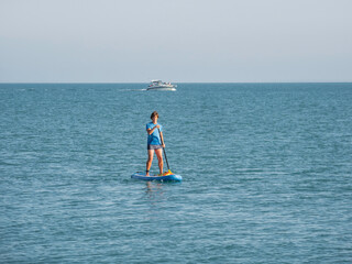 Naklejka premium Paddle boarder. Sportsman paddling on stand up paddleboard. SUP surfing. Active lifestyle. Outdoor recreation. Vacation on seaside.