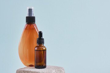 glass dropper bottle and spray cosmetic bottle on concrete podium natural cosmetics and body care concept