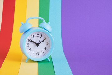 Blue alarm clock on colorul rainbow background
