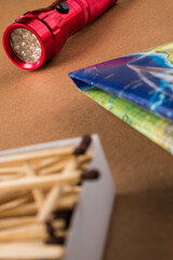 Red flashlight, wooden matches and a map for a forest trip on a wooden table 