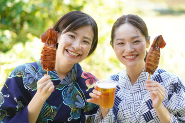 イカ焼きとビールを持つ浴衣女性