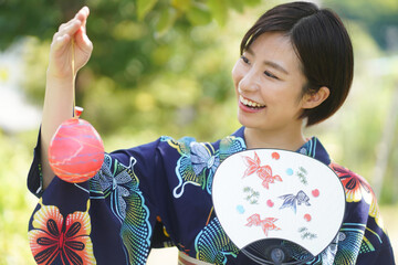 ヨーヨーとうちわを持つ浴衣女性