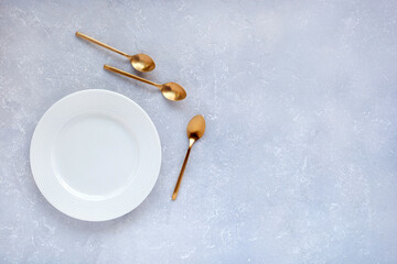 Three golden spoons near an empty plate
