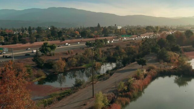 Aerial: Los Gatos Creek County Park and Freeway traffic. Campbell, Silicon Valley, California, USA